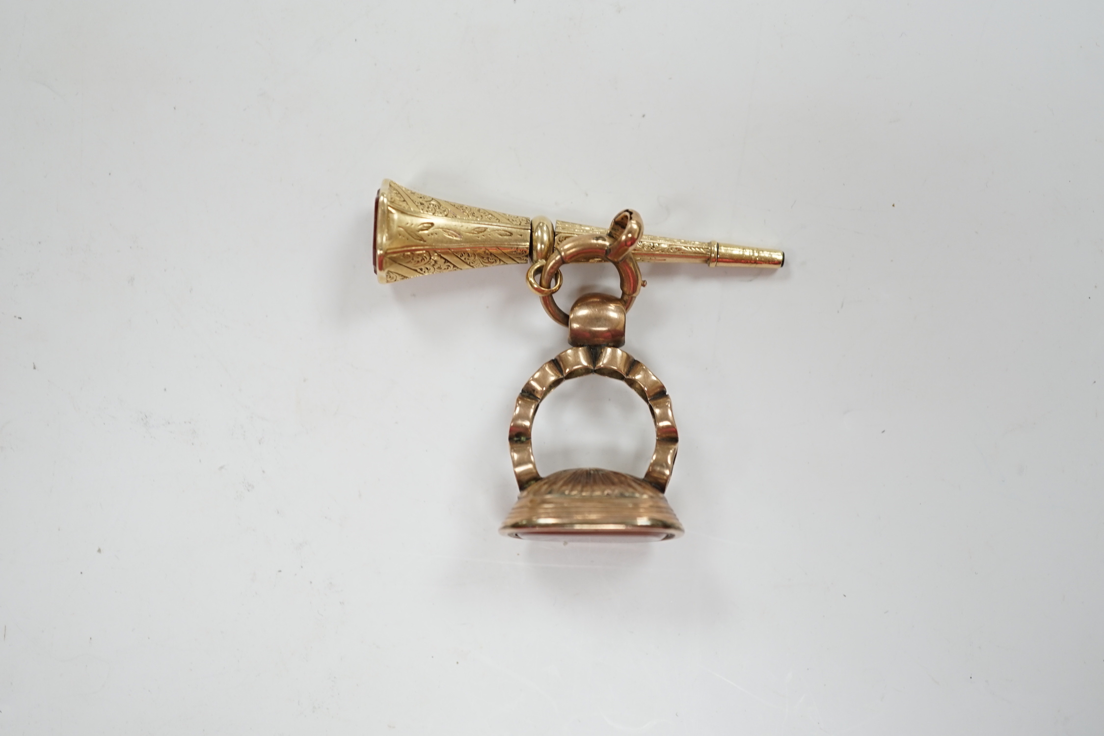 A 19th century engraved yellow metal overlaid and carnelian set trumpet shaped watch key, the matrix carved with crest and initial, 51mm, together with a 19th century gold plated and carnelian set fob.